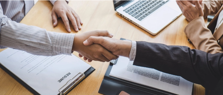 Businessman shaking the hand of new employee with resume